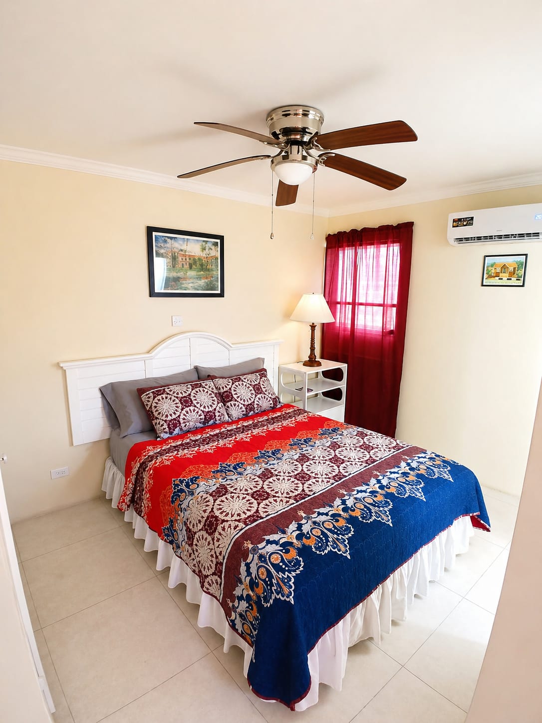 Cozy bedroom with colorful quilt, ceiling fan, and red curtains