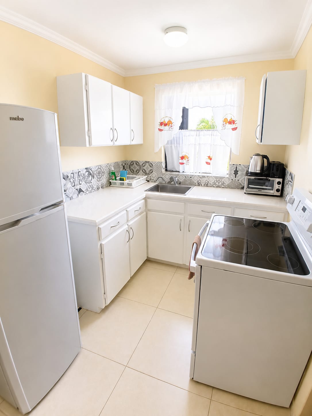Bright compact white kitchen with refrigerator and electric stove