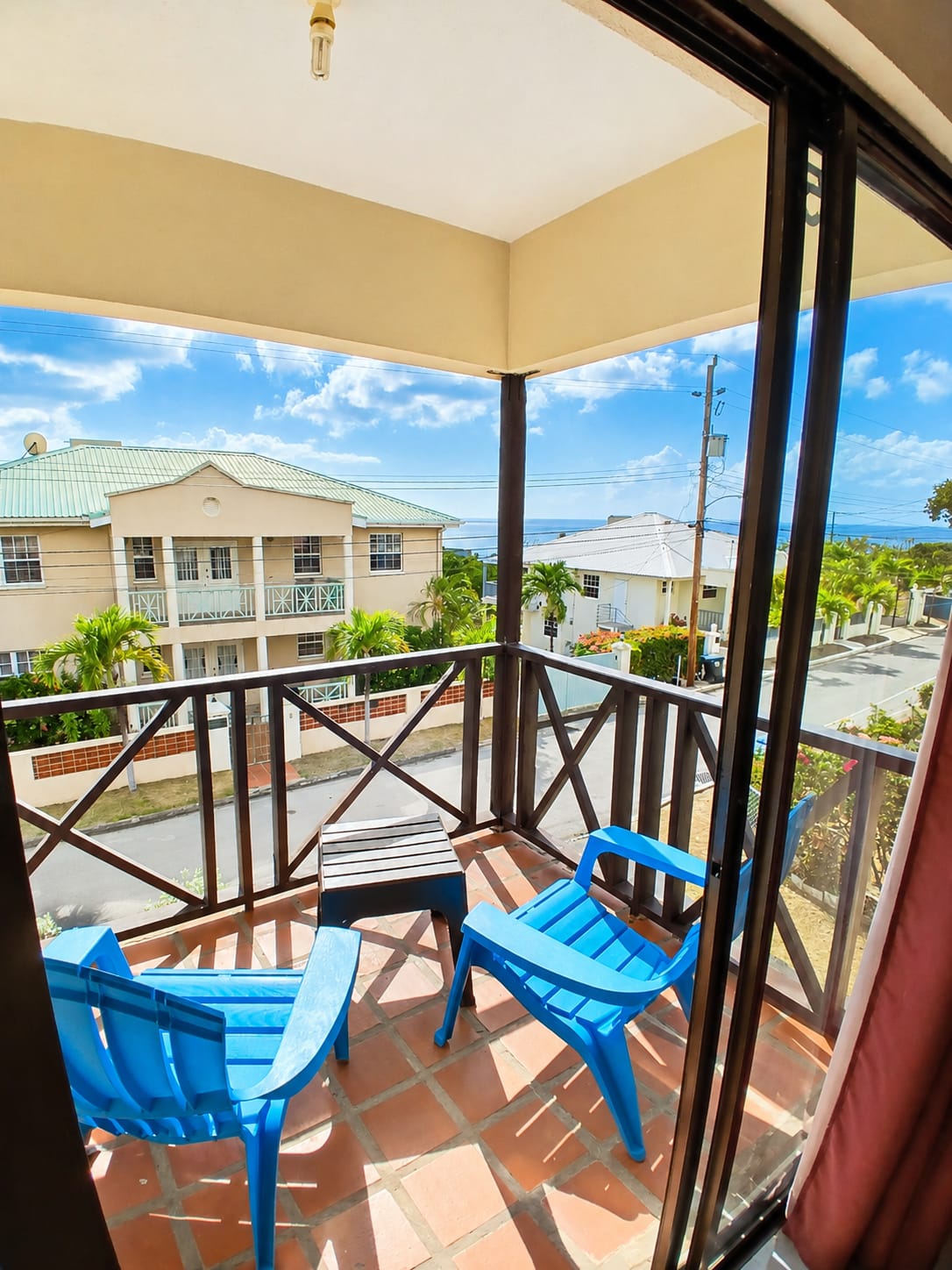 Balcony with blue chairs overlooking tropical neighborhood and ocean
