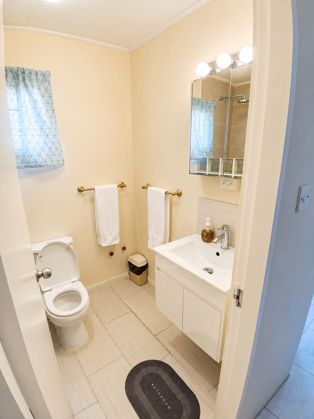 Compact bathroom with toilet, vanity, mirror, and shower